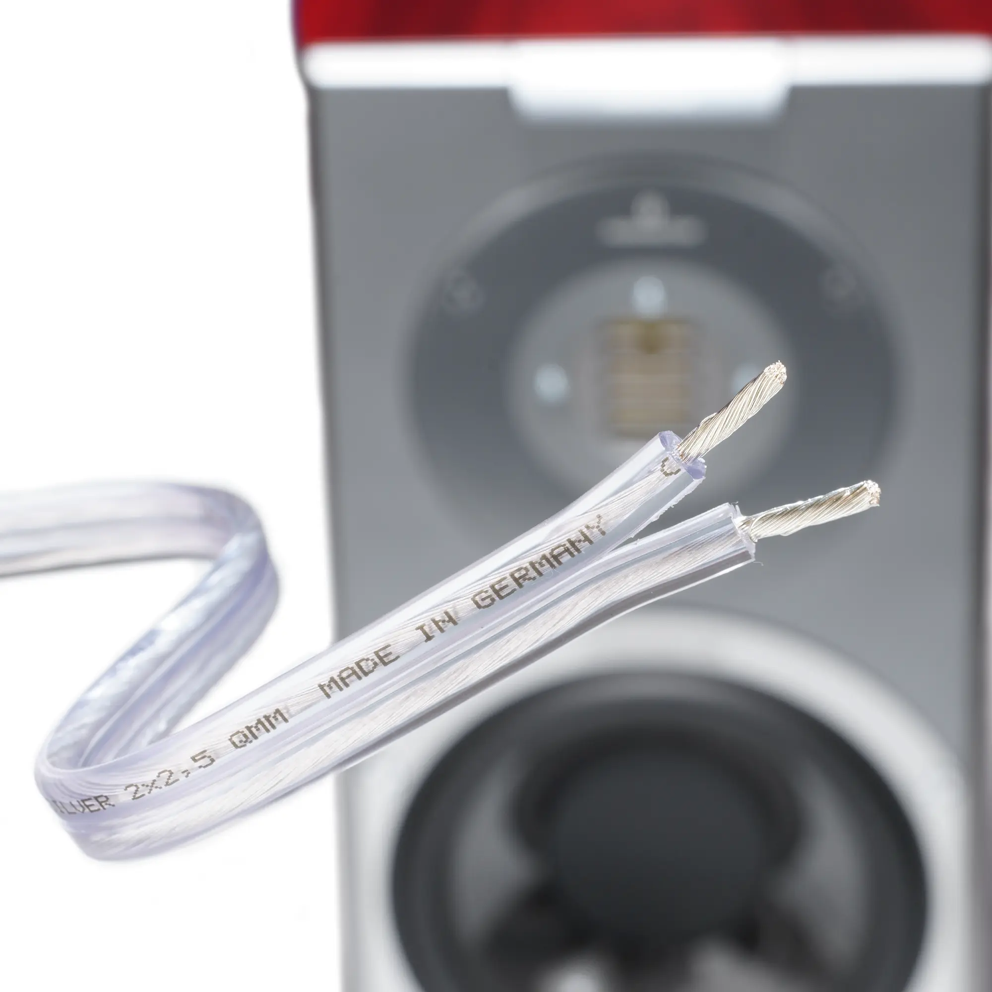 Close-up of the silver cable with exposed silver wires; a speaker is visible in the background.