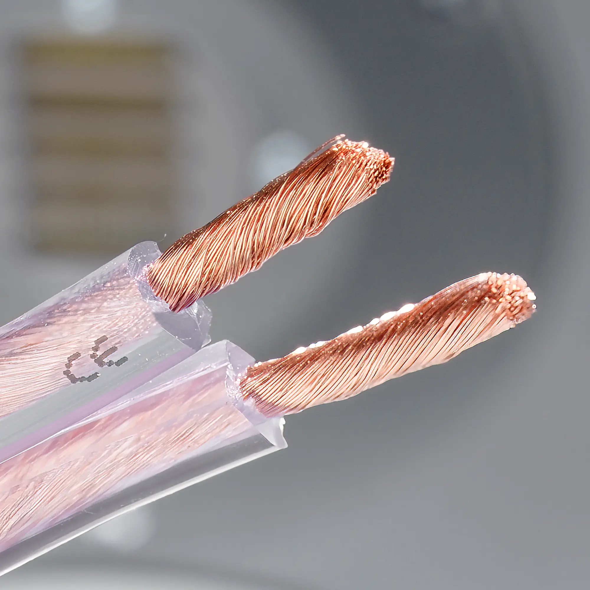 Close-up of the premium copper cable with exposed copper wires, with a speaker in the background.