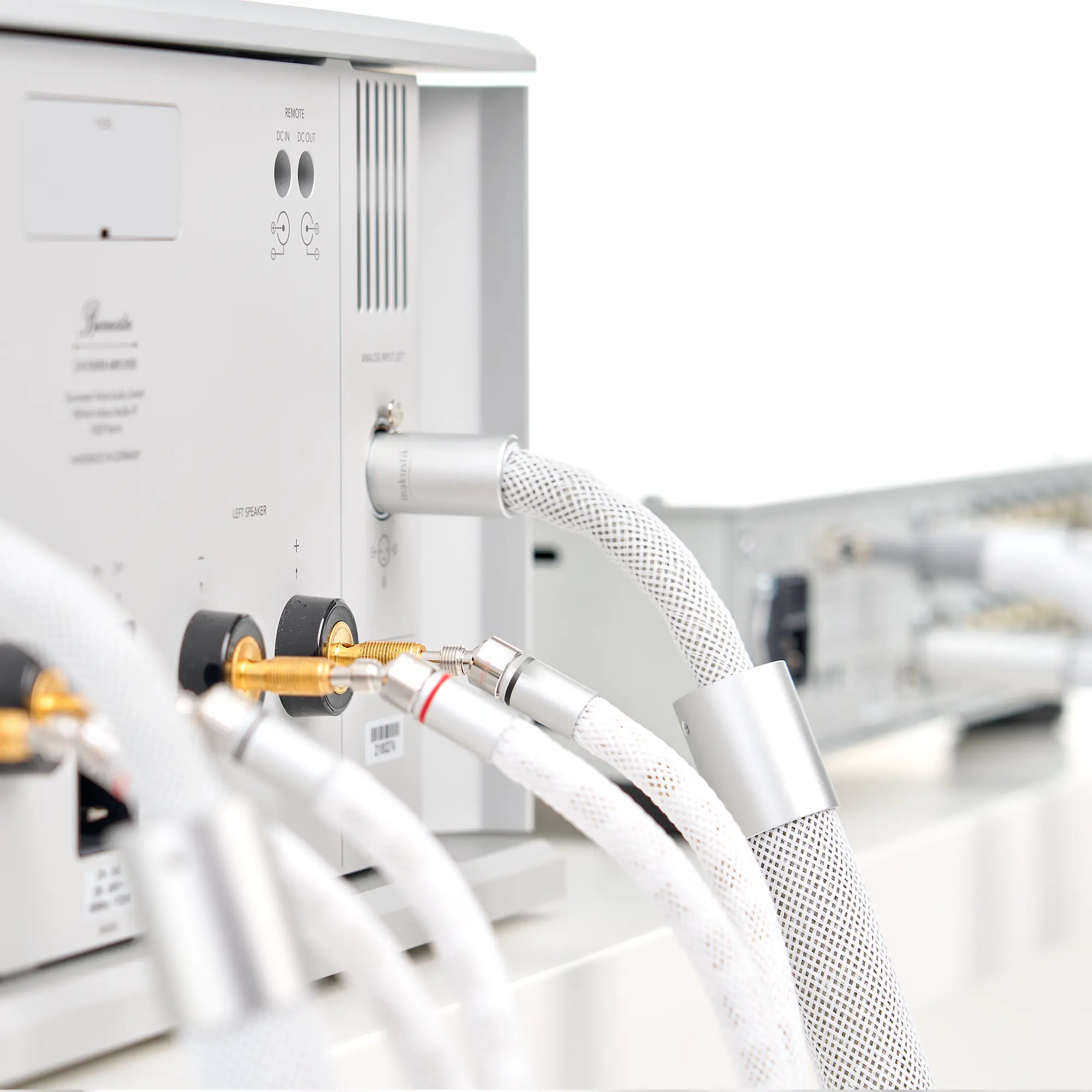 The back of a silver LS-2405 device with several white audio cables connected to it and a thick, braided cable
