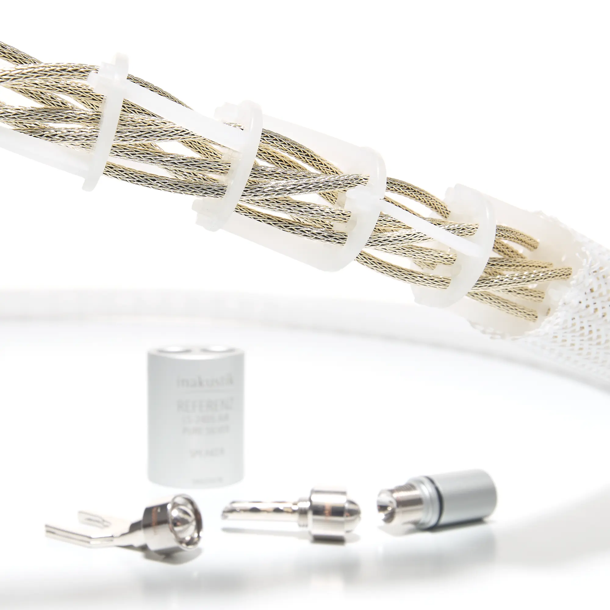 Close-up of the interior of a speaker cable featuring braided silver wires, white plastic clips, and several silver connectors 