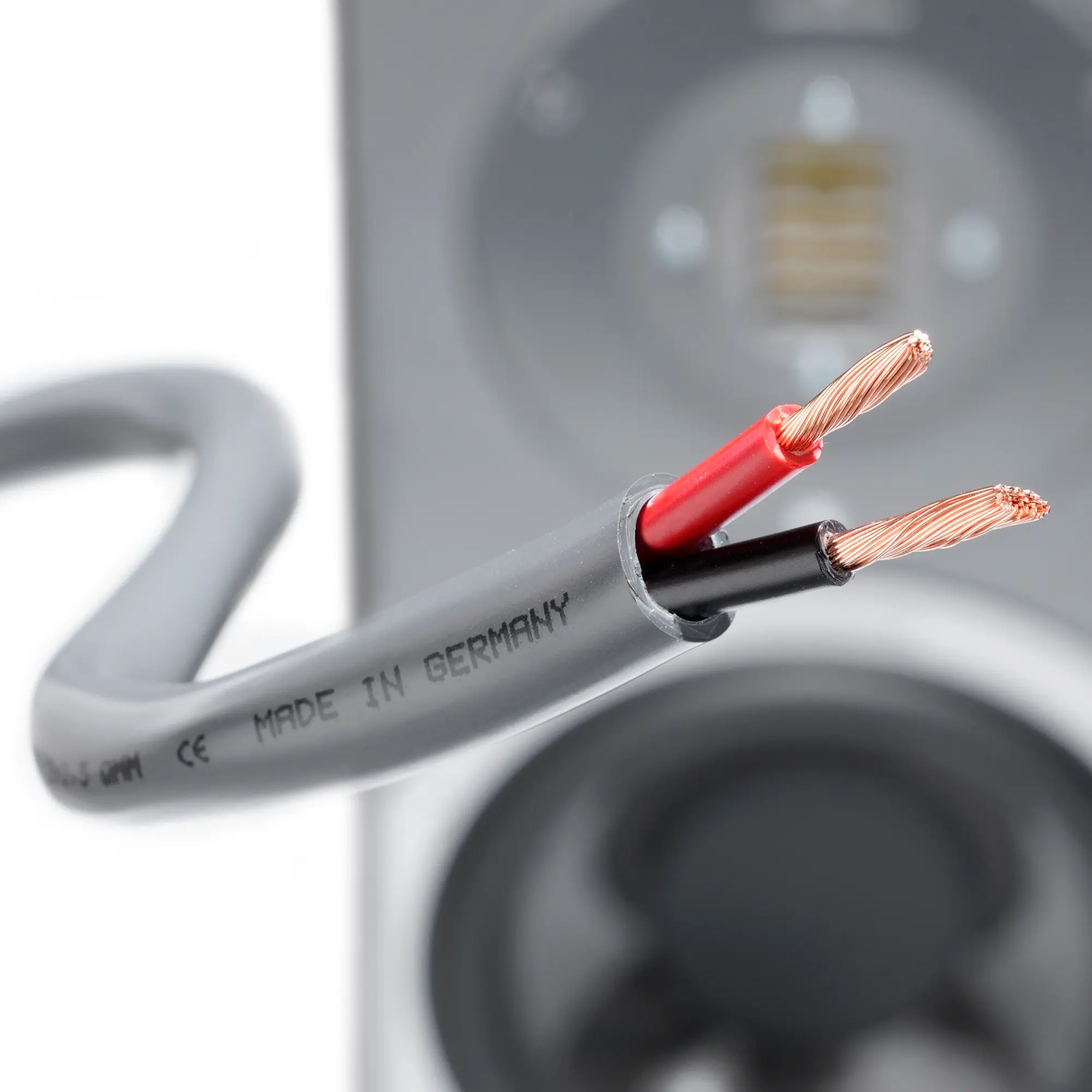 Close-up of the flame-retardant premium speaker cable with exposed strands, with a speaker in the background.