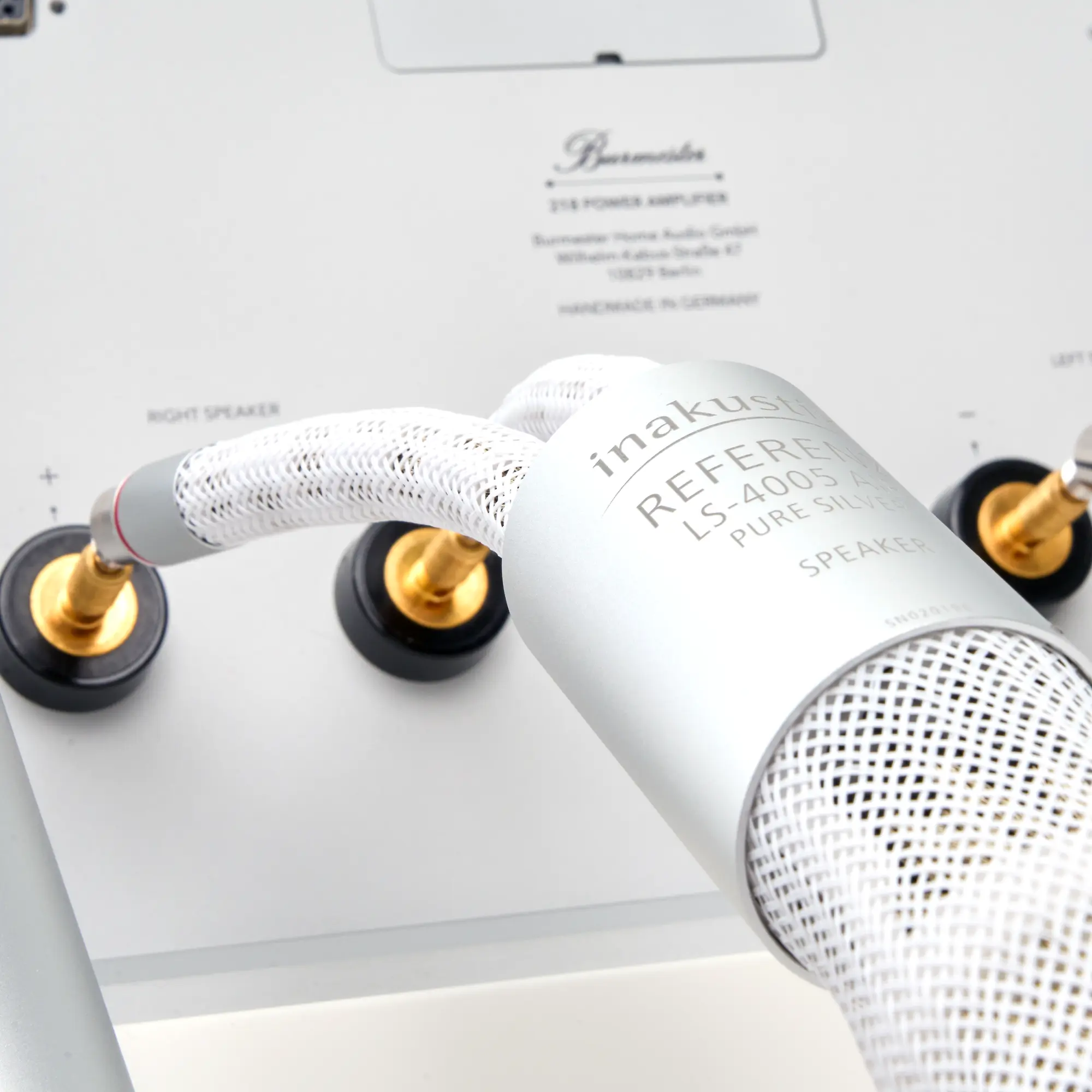 Close-up of the silver speaker cable 4005, labeled “inakustik REFERENCE LS-4005 PURE SILVER,” connected to the gold-colored speaker terminals of a device