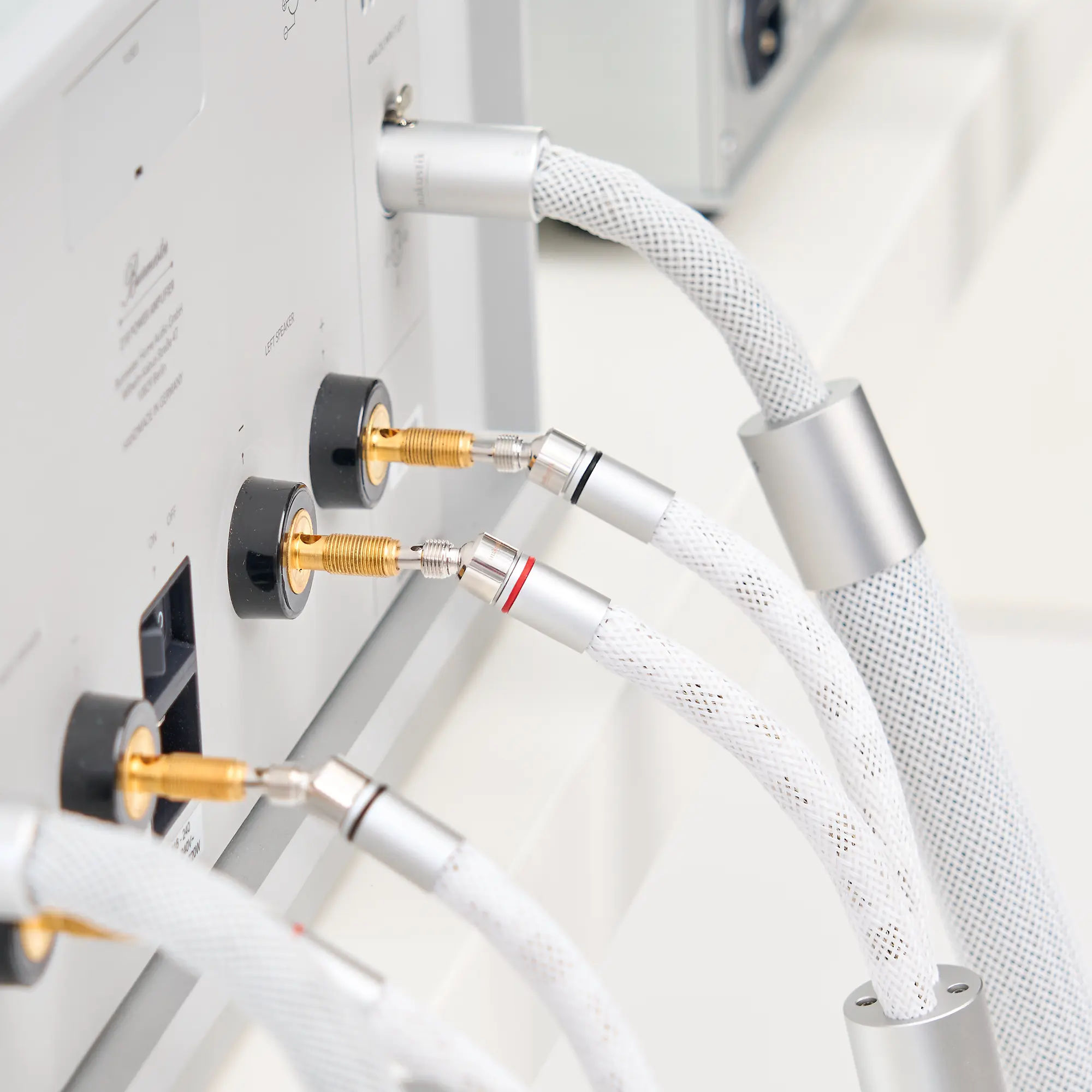 The back of a silver LS-2405 device with several white audio cables connected to it and a thick, braided cable